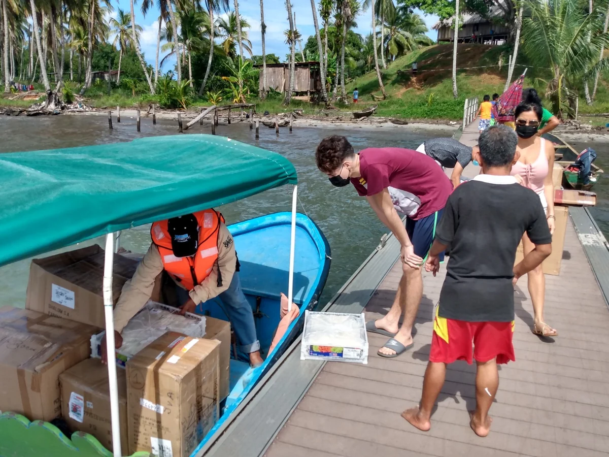 Boxes of Christmas gifts being unloaded from a boat in an island community